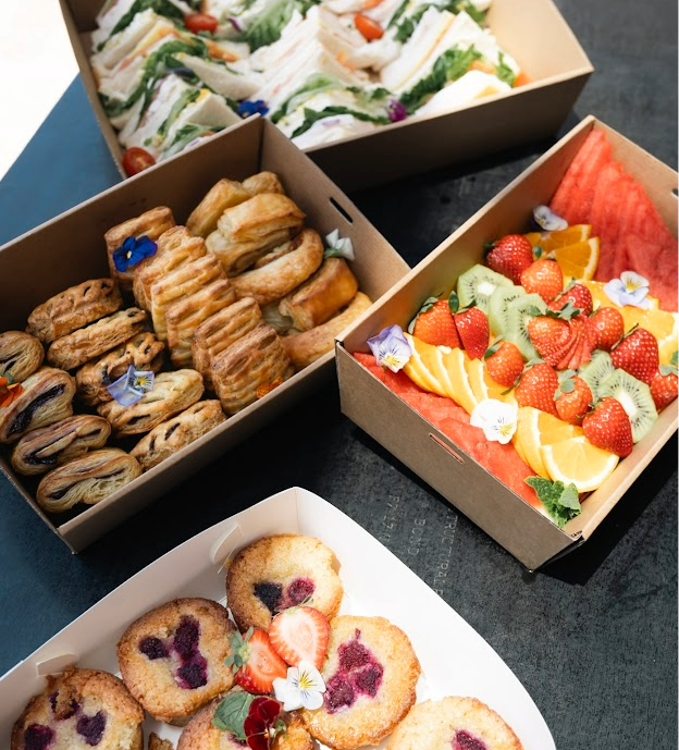 Fresh corporate catering boxes with sandwiches, pastries, fruit and muffins